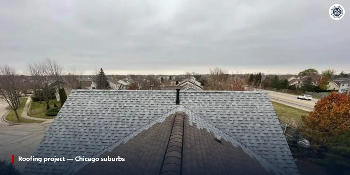 Ridge-level view of a finished shingle roof on a Chicago-suburb house, showing ridge cap and field shingles