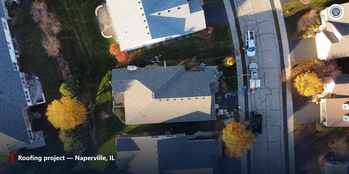 Aerial view of a roofing job in progress in Naperville, IL, with crew trucks and a dumpster on the street