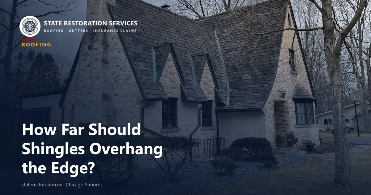Light stone house with a steep dark roof, three small dormers and bare trees around it