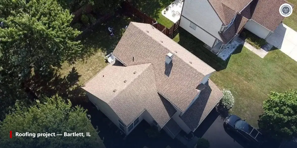 Aerial photo of a finished shingle roof beside a taller two-story house in Bartlett, Illinois