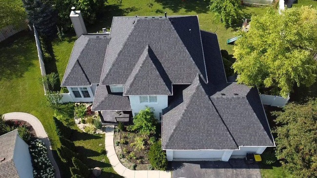 A view of newly installed charcoal gray asphalt shingle roof on a residential home, featuring uniform shingle alignment, clean ridge lines, and precise edge finishing under clear daylight conditions